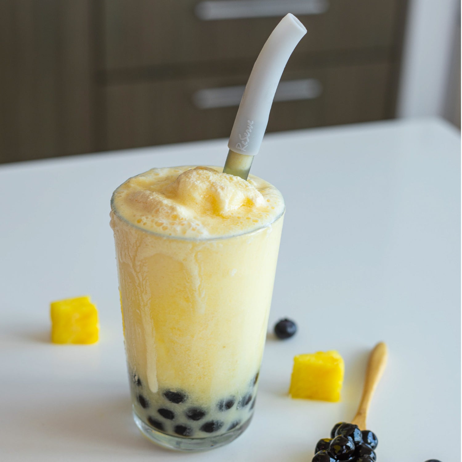 A glass of mango with silver bubble tea straws