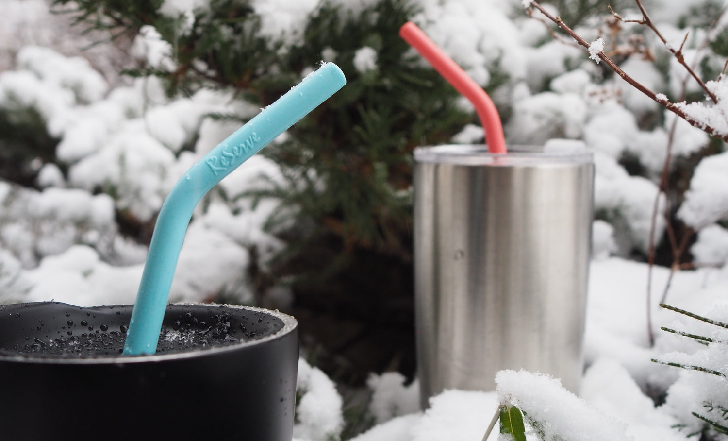 ReServe pink and blue silicone drinking straws in the reusable cups covered by the snow