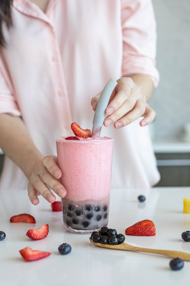 Silver bubble tea straw in a glass of strawberry smoothie with pearl