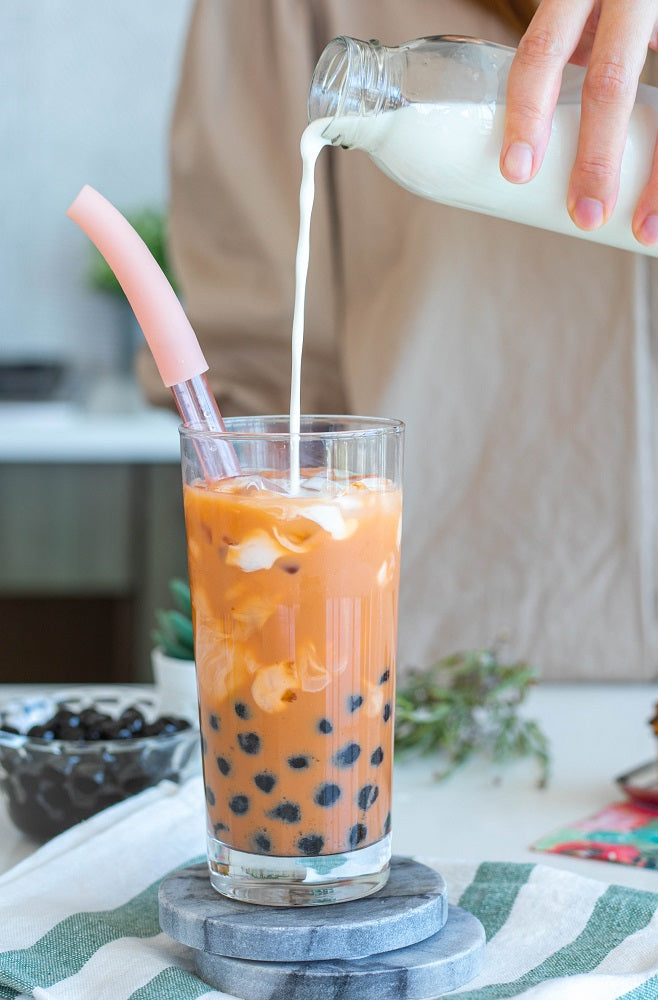 Rose gold bubble tea straw in a glass of Thai Tea with pearl