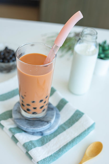 Rose gold bubble tea straw in a glass of Thai Iced Tea with pearl